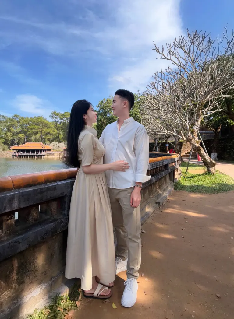 Two people beside a garden pavilion in Huế